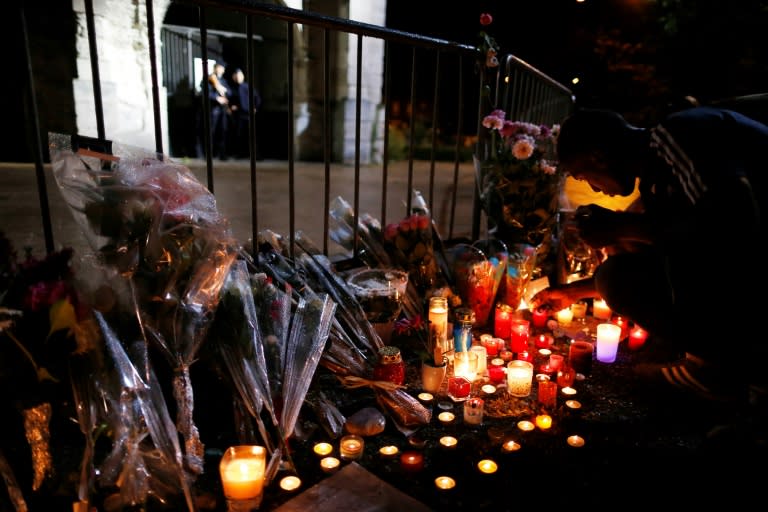 A man lights a candles at a memorial in front of the Saint-Etienne du Rouvray church where priest Jacques Hamel was killed