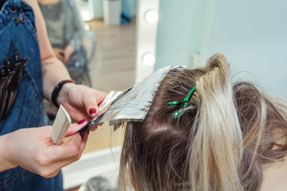 Friseur färbt Foliensträhnchen