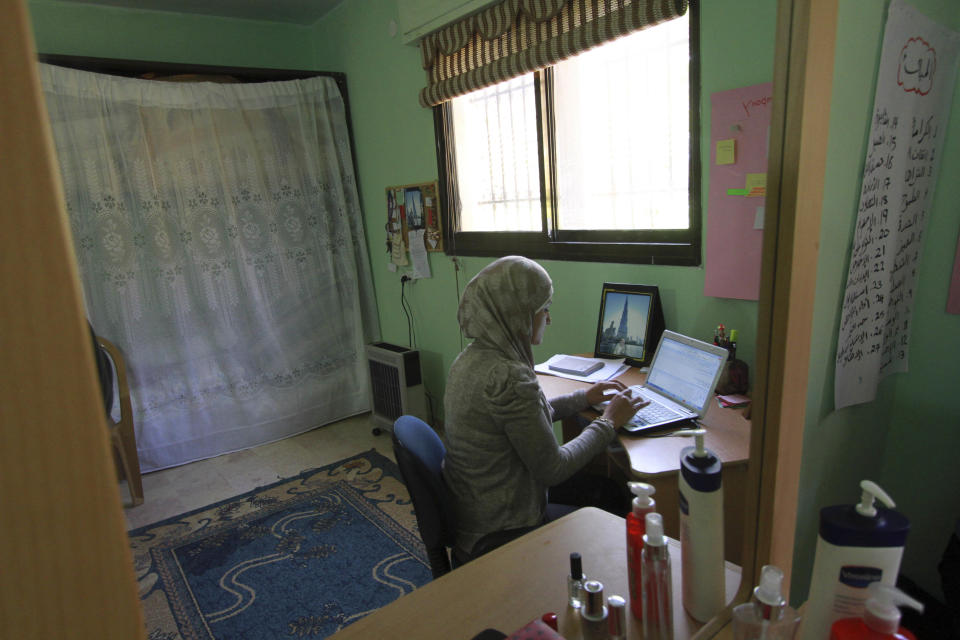 Abeer Abu Ghaith, the first female high-tech entrepreneur in the West Bank, who set up an internet employment brokerage and software development firm, is reflected in a mirror in her home while she works on her laptop in the West Bank village of Dura, Tuesday, Feb. 11, 2014. Palestinian women already make up a majority of students in many colleges and universities in the West Bank and Gaza, but often have trouble transitioning into the job market. (AP Photo/Nasser Shiyoukhi)