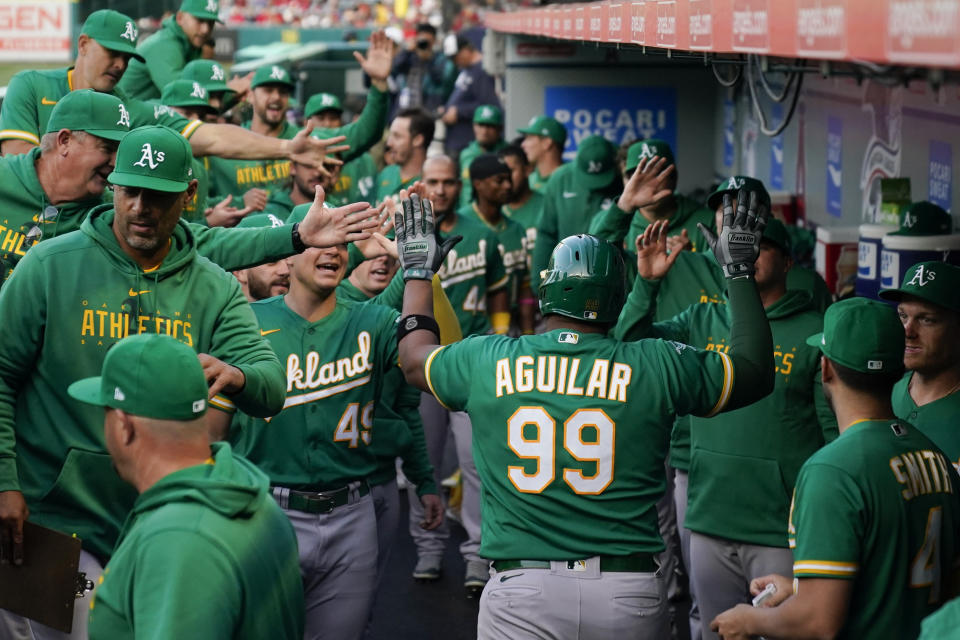 Oakland Athletics' Jesus Aguilar (99) celebrates in the dugout with teammates after hitting a home run during the first inning of a baseball game against the Los Angeles Angels in Anaheim, Calif., Monday, April 24, 2023. (AP Photo/Ashley Landis)