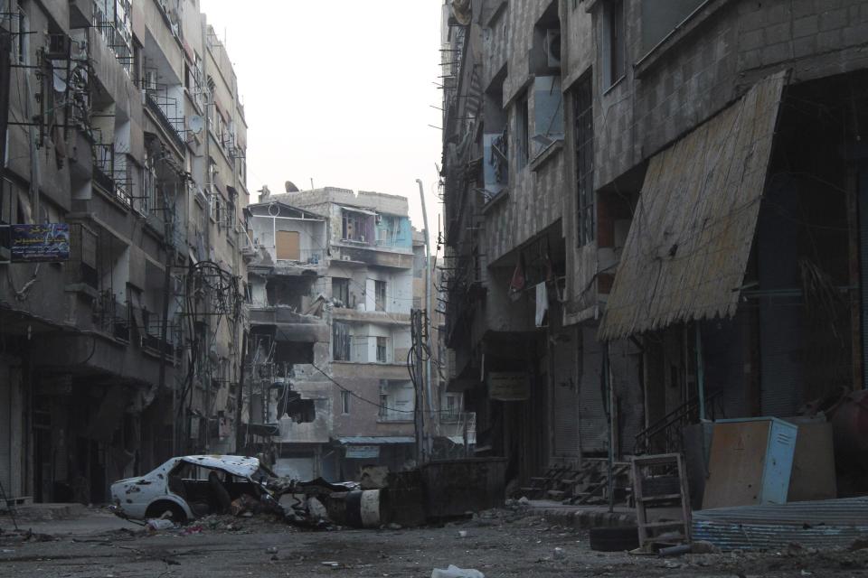 A damaged vehicle and barricade block a deserted street in the Harasta area in eastern al-Ghouta, near Damascus November 22, 2013. REUTERS/William Ismail (SYRIA - Tags: POLITICS CIVIL UNREST CONFLICT)