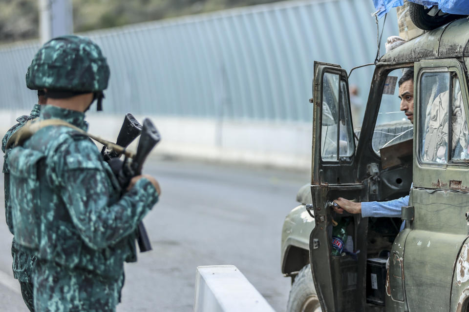 Sergey Astsetryan, an ethnic Armenian resident of Nagorno-Karabakh, right, says goodbye to Azerbaijani border guard servicemen after they checked his Soviet-made vehicle at the Lachin checkpoint on the way from Nagorno-Karabakh to Armenia, in Azerbaijan, Sunday, Oct. 1, 2023. Astsetrayn was one of the last residents of Nagorno-Karabakh to drive out of the region in his own vehicle as part of a grueling weeklong exodus of over 100,000 people — more than 80% of the residents — after Azerbaijan reclaimed the area in a lightning military operation. (AP Photo/Aziz Karimov)