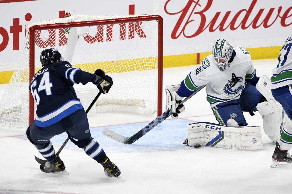 Vancouver Canucks goaltender Thatcher Demko (35) makes a save on Winnipeg Jets' Logan Stanley (64) during the third period of an NHL game in Winnipeg, Manitoba, Monday, May 10, 2021. (Fred Greenslade/The Canadian Press via AP)