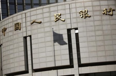 A fluttering Chinese national flag casts its shadow on the headquarters of the People's Bank of China, China's central bank, in central Beijing November 24, 2014. REUTERS/Kim Kyung-Hoon