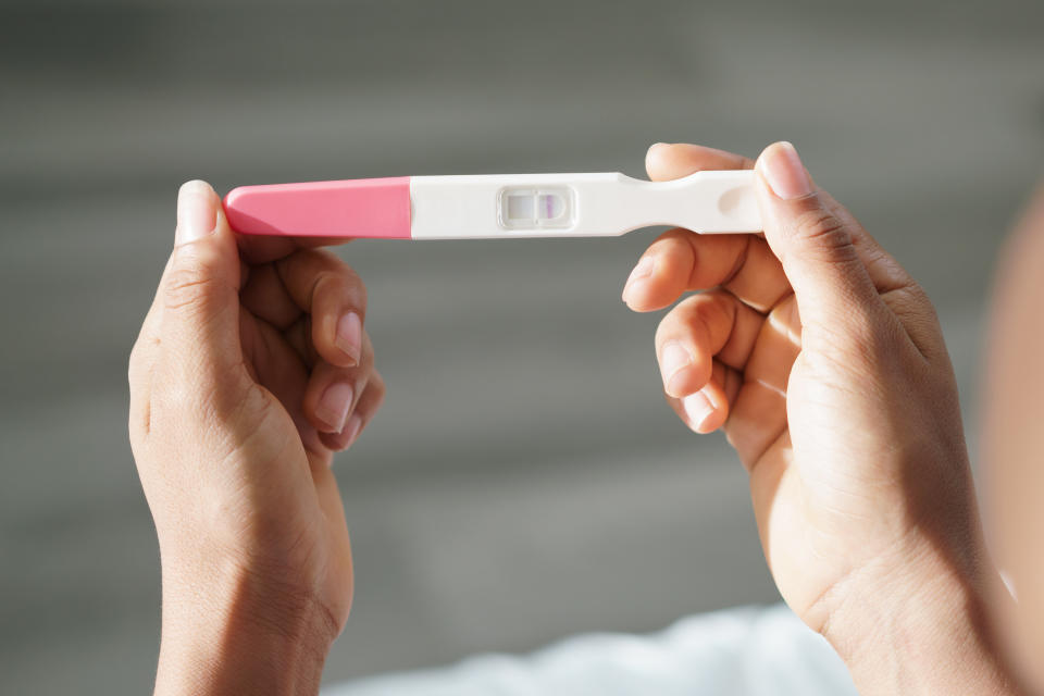 Black woman holding negative pregnancy test. Close-up of hands and kit