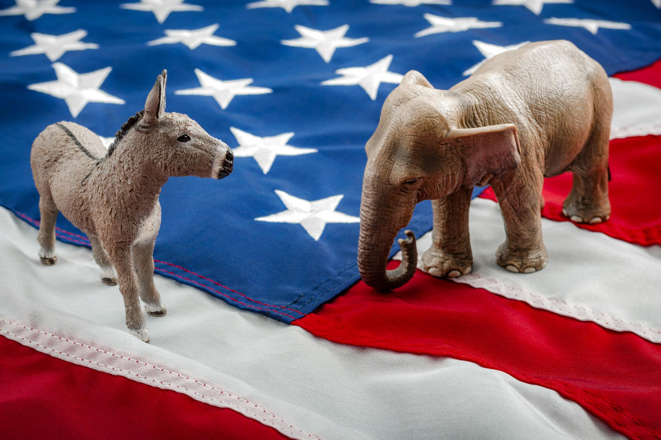 A Democratic donkey and Republican elephant squaring off atop the American flag.