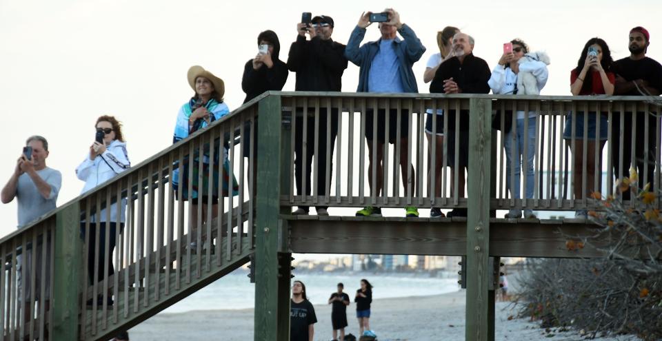 Spectators along the beach across from Patrick Space Force Base watch Sunday's SpaceX Bandwagon-1 launch and first-stage booster landing.