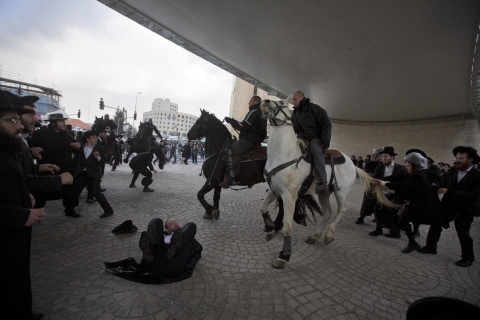 Israeli police officers on horses disperse a crowd of ultra-Orthodox Jewish men during a demonstration in Jerusalem, Thursday, Feb. 6, 2014. Israeli police said thousands of ultra-Orthodox Jews are blocking highways across the country to protest plans to enlist them into the military. (AP Photo/Sebastian Scheiner)