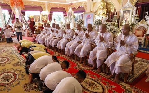 The team bow before novice Buddhist monks during the ceremony - Credit: AFP