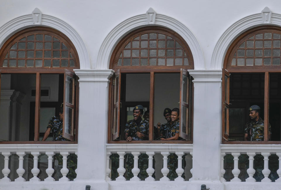 Army soldiers enjoy a lighter moment as protesters leave prime minister Ranil Wickremesinghe's office building in Colombo, Sri Lanka, Thursday, July 14, 2022. Sri Lankan protesters retreated from government buildings they seized and military troops reinforced security at the Parliament on Thursday, establishing a tenuous calm in a country in both economic meltdown and political limbo.(AP Photo/Rafiq Maqbool)