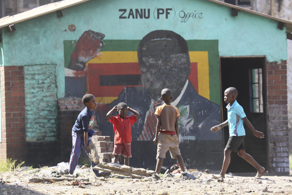 Children play next to a defaced portrait of Former Zimbabwean President Robert Mugabe in Harare, Friday, Sept, 6 2019. Robert Mugabe, the former leader of Zimbabwe forced to resign in 2017 after a 37-year rule whose early promise was eroded by economic turmoil, disputed elections and human rights violations, has died. He was 95. (AP Photo/Tsvangirayi Mukwazhi)