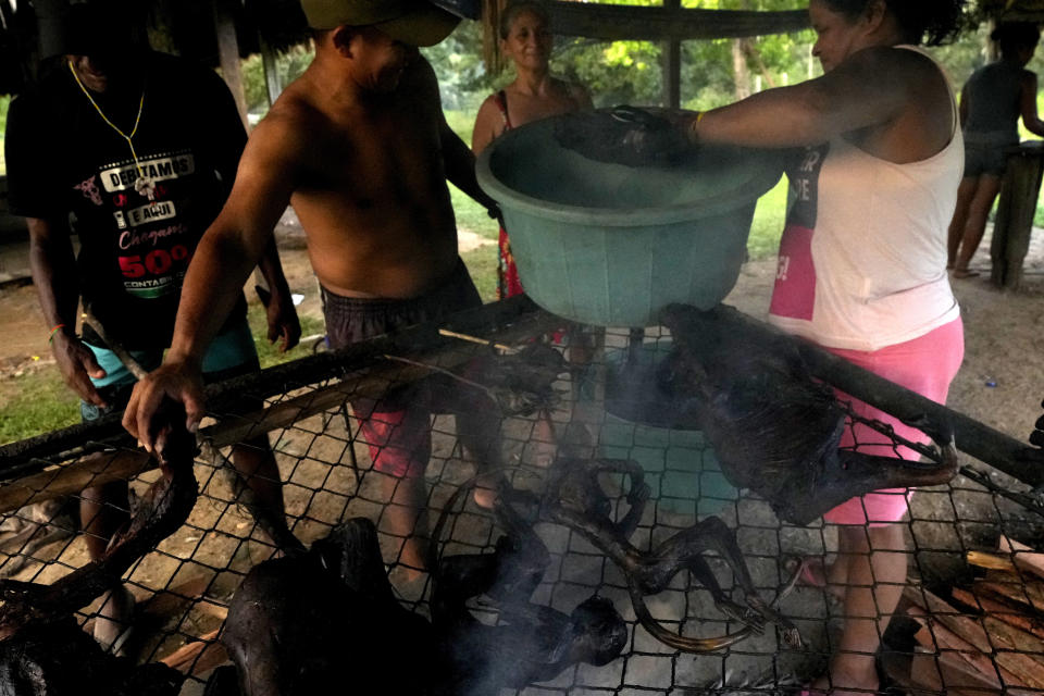 Community members collect meat from a grill to prepare Moqueada, a traditional Tembe food made with game meat, during the Wyra'whaw coming-of-age festival in the Ramada ritual center, in Tenetehar Wa Tembe village, located in the Alto Rio Guama Indigenous territory in Para state, Brazil, Friday, June 9, 2023. Known as the Menina Moca in Portuguese, the three-day festival starts Friday and is for adolescent boys and girls in Brazil's Amazon. (AP Photo/Eraldo Peres)
