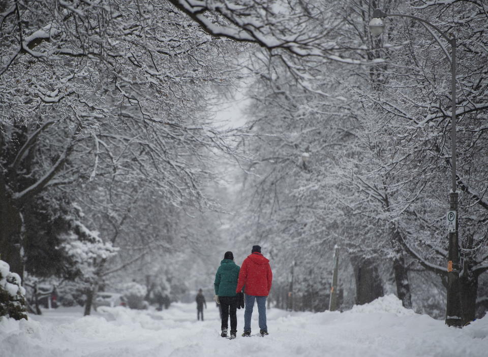 People walk on the snow-covered street in Ottawa's Glebe neighbourhood during a major snowstorm on Saturday, Jan. 16, 2021. (Justin Tang/The Canadian Press via AP)