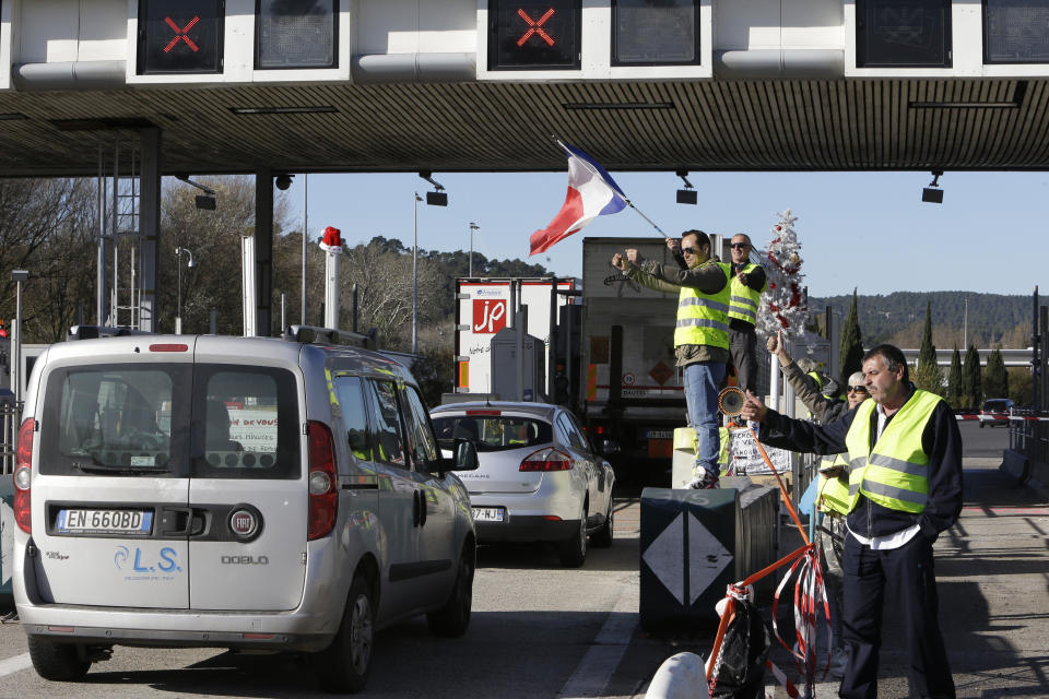 Demonstrators wearing yellow vests open the toll gates on a motorway near Aix-en-Provence, southeastern France, Tuesday, Dec. 4, 2018. French Prime Minister Edouard Philippe announced a suspension of fuel tax hikes Tuesday, a major U-turn in an effort to appease a protest movement that has radicalized and plunged Paris into chaos last weekend. (AP Photo/Claude Paris)