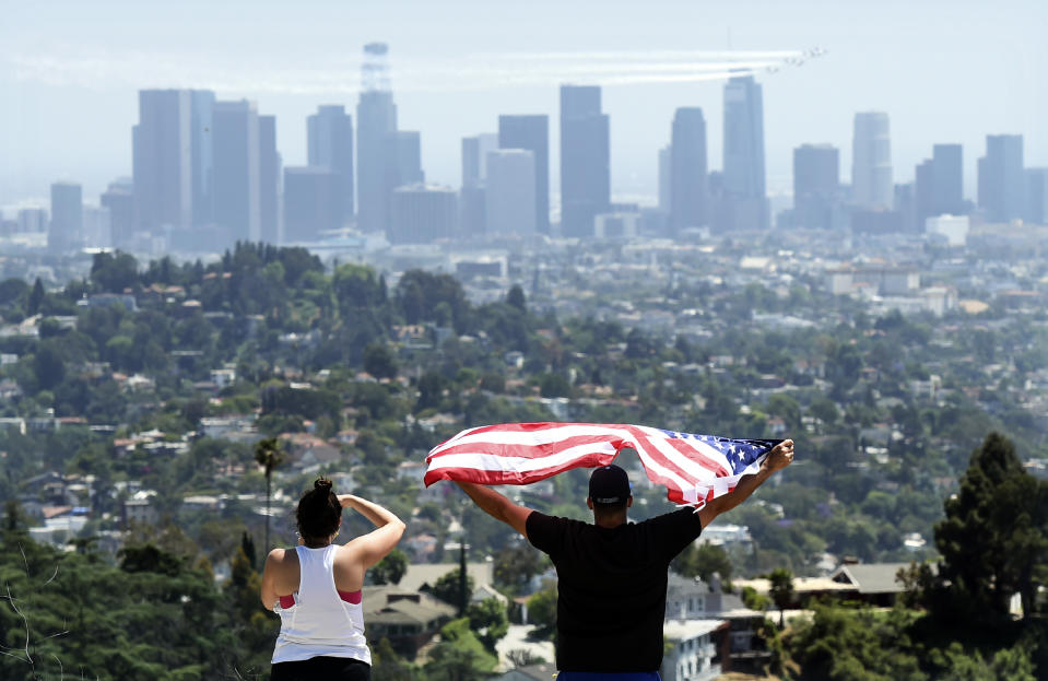 FILE - In this May 15, 2020, file photo, a couple salute the United States Air Force Thunderbirds who fly over downtown Los Angeles to honor frontline COVID-19 responders at Griffith Park in Los Angeles. (AP Photo/Chris Pizzello, File)