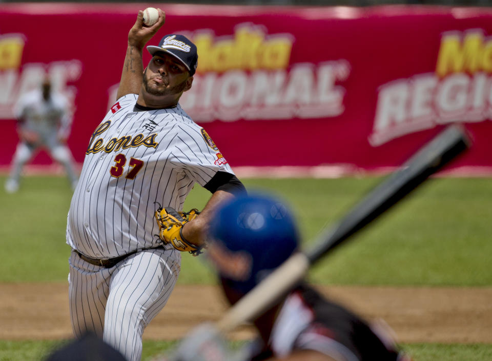 In this Oct. 12, 2018 photo, Leones de Caracas' starting pitcher Luis Diaz throws to Tiburones de la Guaira's Junior Sosa during the first inning of the season's opening baseball game in Caracas, Venezuela. While many of the 70-plus Venezuelan players on big league rosters return home for a few games each season, most arriving this year are little known and don't reflect the nation's powerhouse talent. (AP Photo/Fernando Llano)