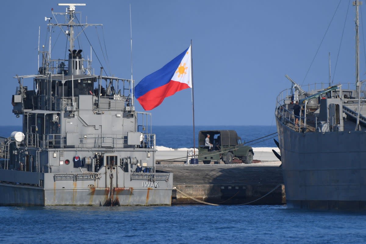 This photo taken on April 21, 2023 shows a Philippine flag fluttering next to navy ships anchored at the Philippine-occupied Thitu island in the disputed South China Sea (AFP via Getty Images)