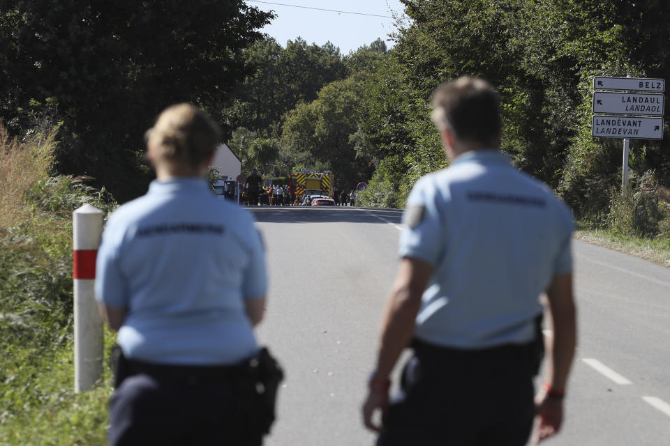 French gendarmes block the road leading the site of a jet crash near Pluvigner, western France, Thursday, Sept.19, 2019. A Belgian F-16 fighter jet crashed in western France, damaging a house, setting a field ablaze and leaving a pilot suspended for two hours from a high-voltage electricity line after his parachute got caught, according to French authorities. (AP Photo/David Vincent)
