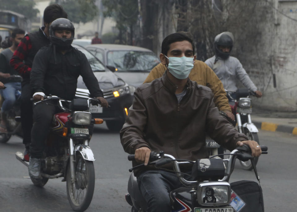 A motorcyclists wears face mask as heavy smog blankets Lahore, Pakistan, Thursday, Nov. 21, 2019. Amnesty International issues "Urgent Action" saying every person in Lahore at risk. Heavy smog has enveloped many cities of Punjab province, causing highway accidents and respiratory problems, and forcing many residents to stay home. (AP Photo/K.M. Chaudary)