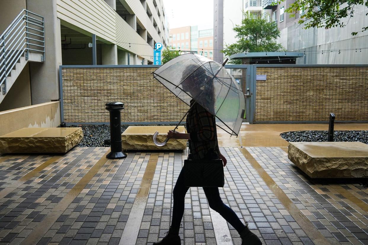 Camilla Stoner walks with her umbrella at the Domain in Austin during a rain shower Sept. 13. The Austin area is expected to get rain throughout this week, perhaps as much as 4 inches.