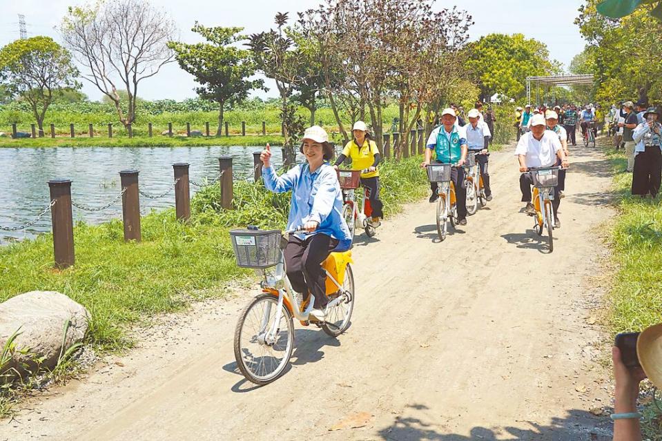 屏東縣長周春米（前）在風景優美的海豐溼地生態池騎單車，響應世界地球日。（羅琦文攝）