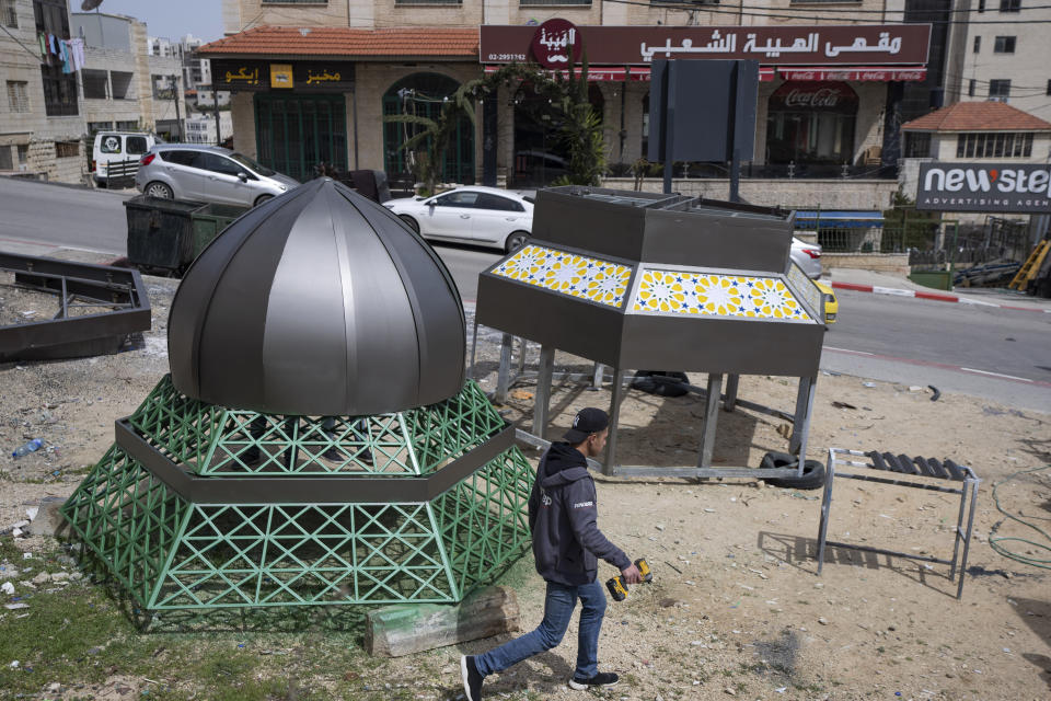 Palestinian labors work on an Islamic style monument that consists of lantern and a crescent, two symbolic icons of the Islamic holy month of Ramadan, in the West Bank city of Ramallah, Tuesday, March 29, 2022. The monument is built by the municipality of Ramallah to decorate a main square at the center of the city, where it will be illuminated during a mass event to celebrate the upcoming Ramadan. (AP Photo/Nasser Nasser)