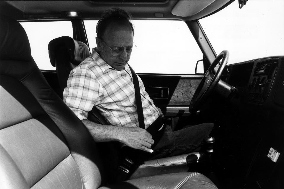 Un conductor se ajusta el cinturón de seguridad de su auto a mediados de la década de 1980. (Getty Images)