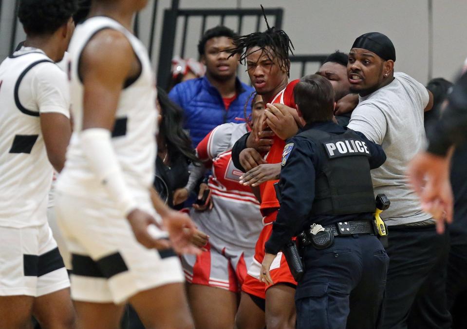 A North Ridgeville police officer pulls East's Ronan Kelly, facing, off a Buchtel player during a bench-clearing brawl in the final moments of the third quarter of a Division II district semifinal on Wednesday in North Ridgeville. [Jeff Lange/Beacon Journal]