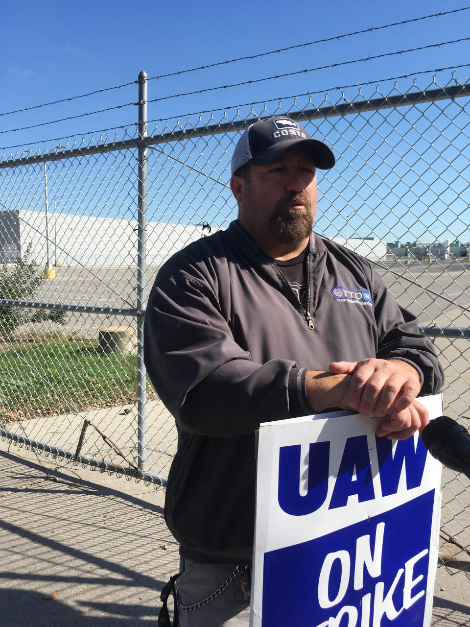 In this Tuesday, Oct. 8, 2019, photo, striking General Motors worker Mike Armentrout stands on the picket line outside a transmission plant in Toledo, Ohio. Workers say they are starting to feel the pinch of going without their regular paychecks. (AP Photo/John Seewer)