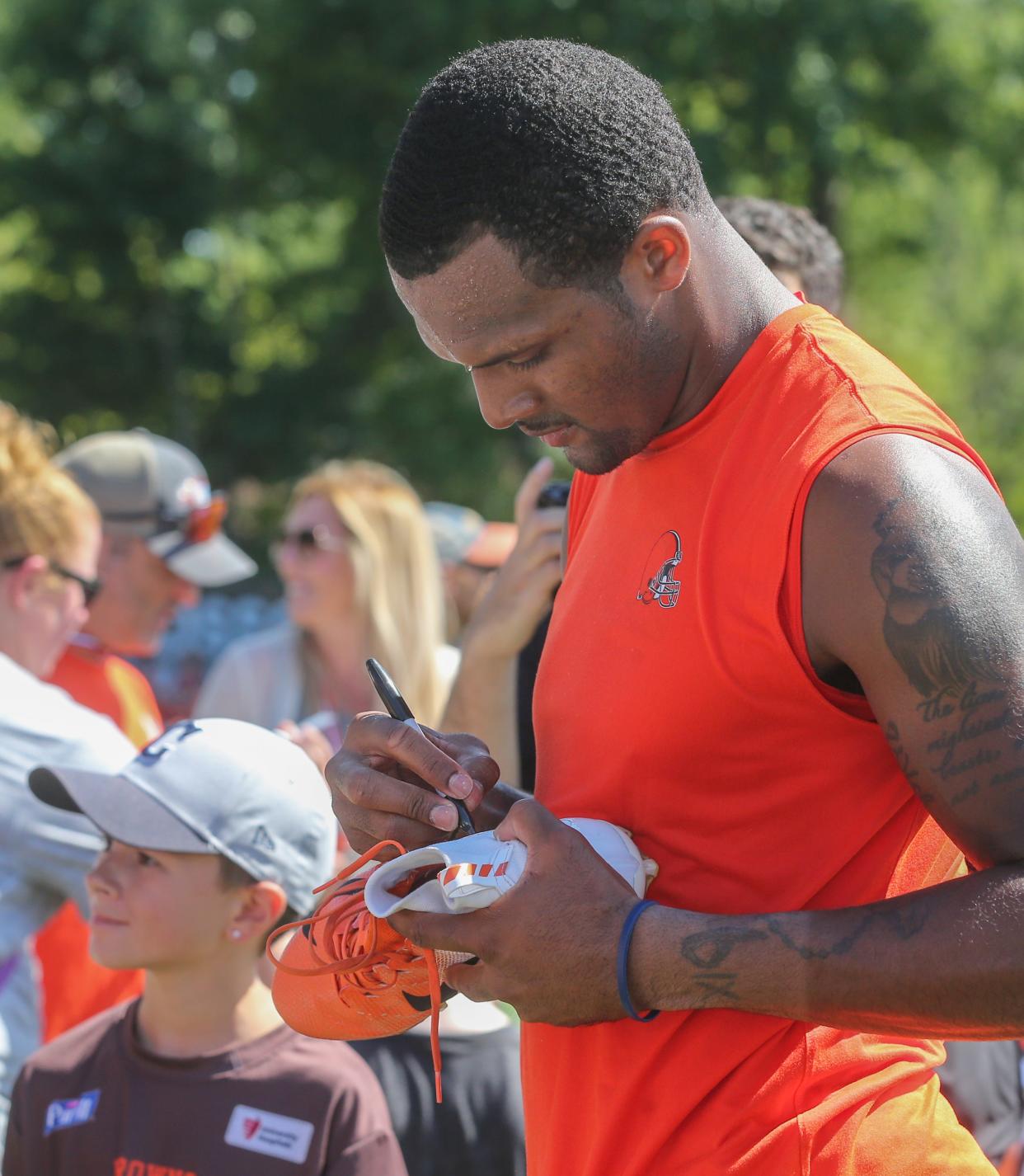 Cleveland Browns quarterback Deshaun Watson signs one of his shoes for a child after training camp on Saturday, July 30, 2022 in Berea.