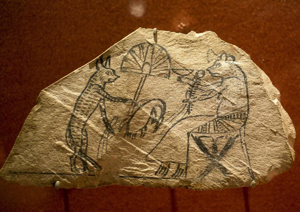 In this March 20, 2014 photo, a limestone with pigment shows a scene of a cat and mouse, in which animals perform human tasks, is displayed as part of the exhibit "Soulful Creatures: Animal Mummies in Ancient Egypt," at the Orange County's Bowers Museum in Santa Ana, Calif. The exhibition is on the ancient the mummification of animals in the Egyptian culture and religion. Drawn from the renowned collections of the Brooklyn Museum, Soulful Creatures features choice examples from among the many millions of mummies of birds, cats, dogs, snakes, and other animals preserved from at least thirty-one different cemeteries throughout Egypt. (AP Photo/Damian Dovarganes)