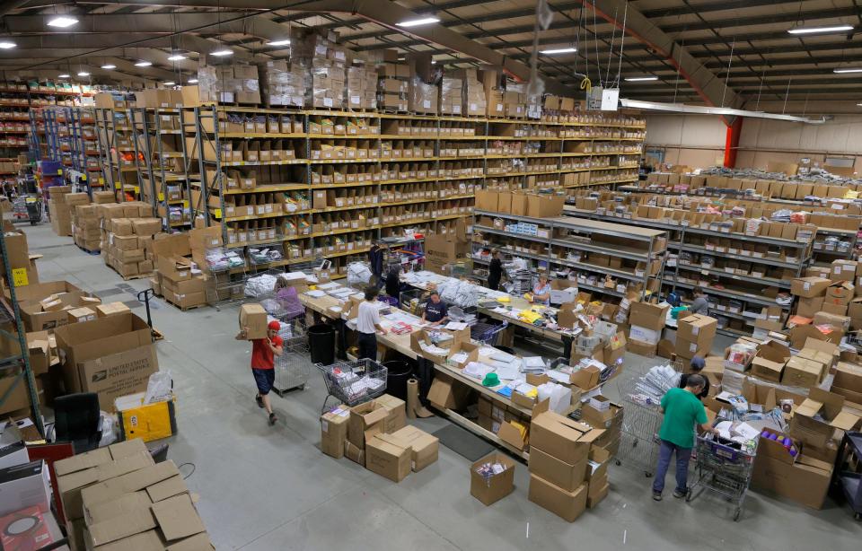 Workers fulfill and pack up online orders at UglyChristmasSweater.com inside the 42,000 square foot warehouse in Commerce Township, Mich., on Oct. 12, 2021. The online retail store has a large supply of Christmas sweaters and other items stuck on freighters off the coast of California.