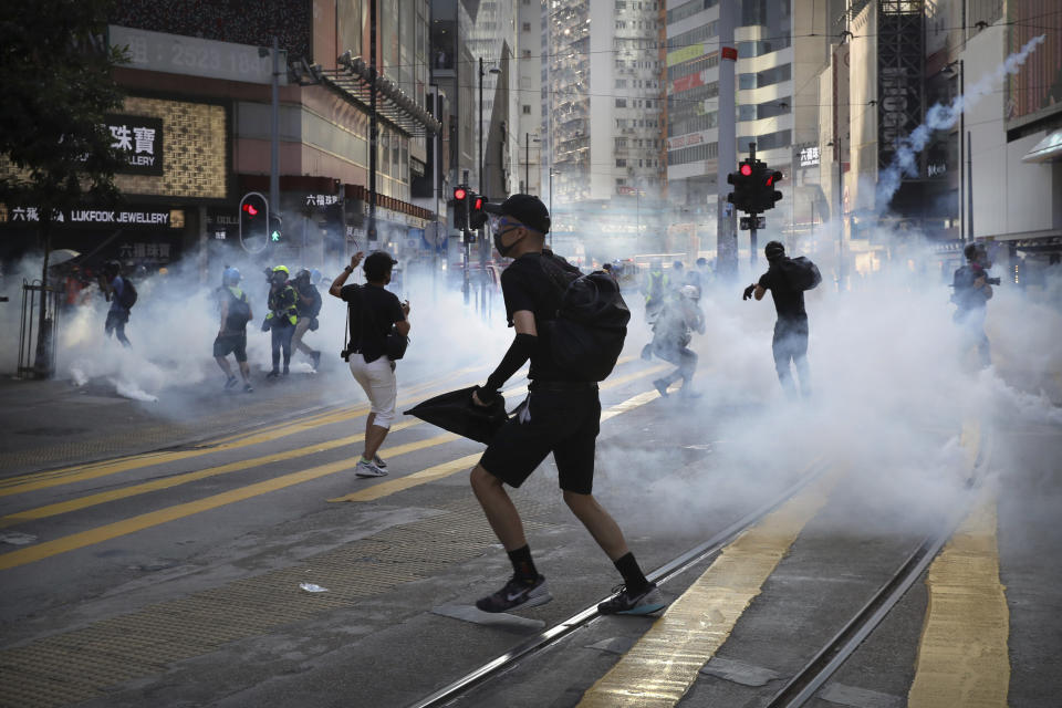Demonstrators react as police fire tear gas during a protest in Hong Kong, Saturday, Nov. 2, 2019. Hong Kong riot police fired multiple rounds of tear gas and used a water cannon Saturday to break up a rally by thousands of masked protesters demanding meaningful autonomy after Beijing indicated it could tighten its grip on the Chinese territory. (AP Photo/Kin Cheung)