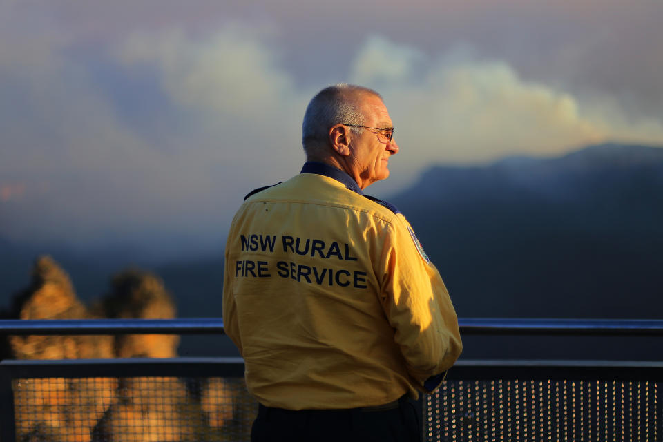 A NSW Rural Fire Service crew member looks out at the smoke-shrouded Three Sisters.