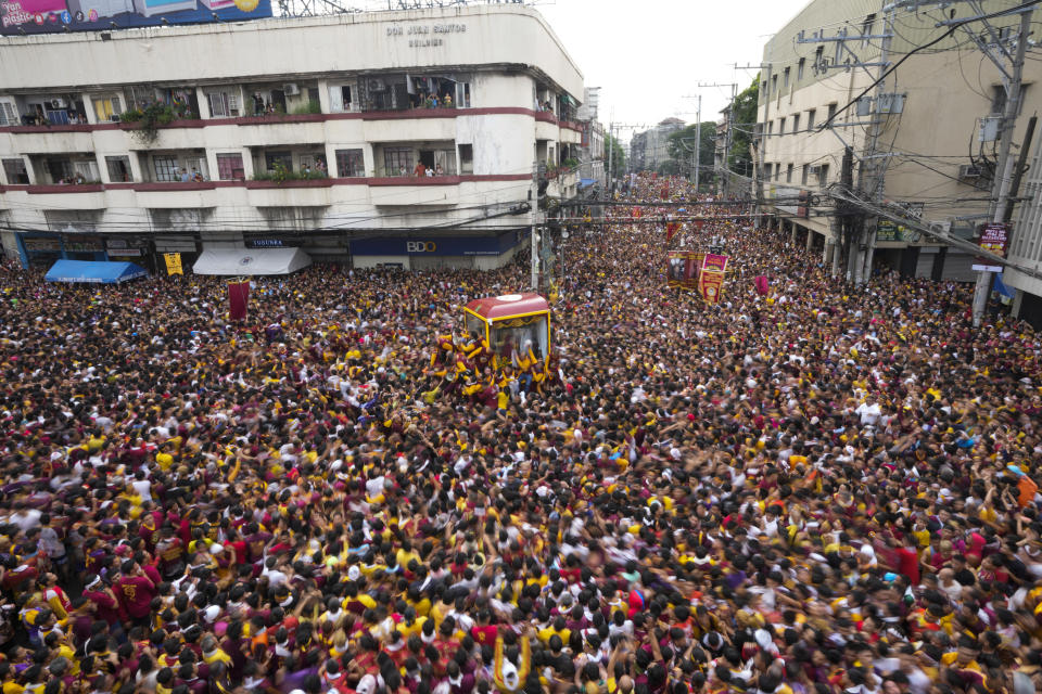 A glass-covered cart carrying the Black Nazarene makes its way through the crowd during it's annual procession which was resumed after a three-year suspension due to the coronavirus pandemic on Tuesday, Jan. 9, 2024 in Manila, Philippines. A mammoth crowd of mostly barefoot Catholic devotees joined a chaotic procession through downtown Manila Tuesday to venerate a centuries-old black statue of Jesus Christ with many praying for peace in the Middle East where Filipino relatives work. (AP Photo/Aaron Favila)