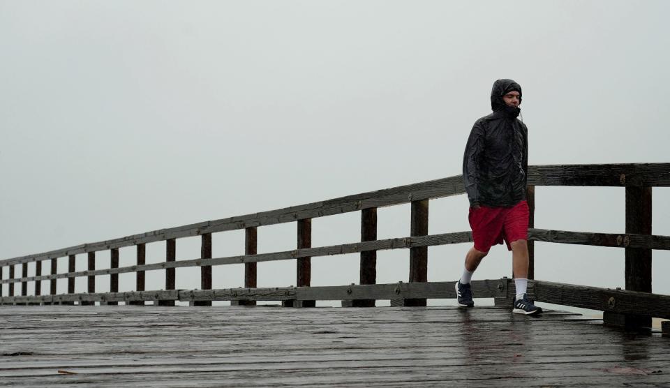Port Hueneme resident Eric Karpowich walks on the Hueneme Pier's open section amid stormy weather on Feb. 4. Another storm is expected to bring periods of heavy rain to Ventura County starting Sunday night.