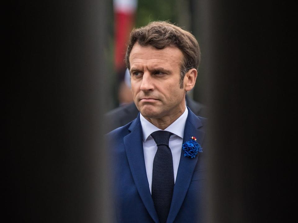 Emmanuel Macron stands between two black walls