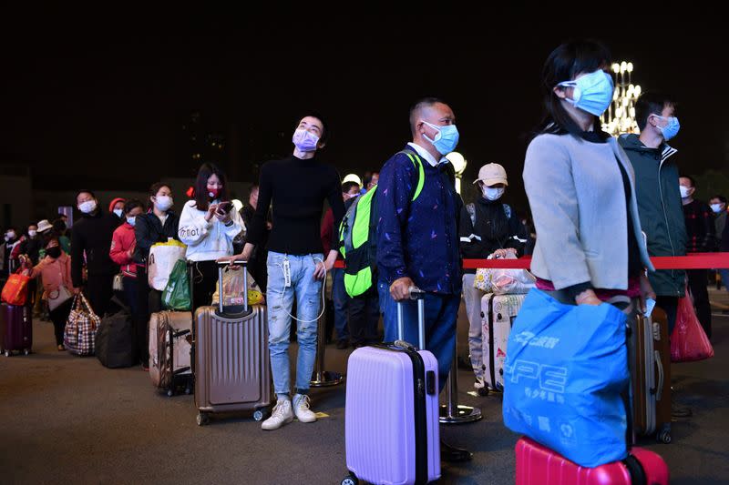 Travellers line up with their belongings outside Wuchang Railway Station in Wuhan