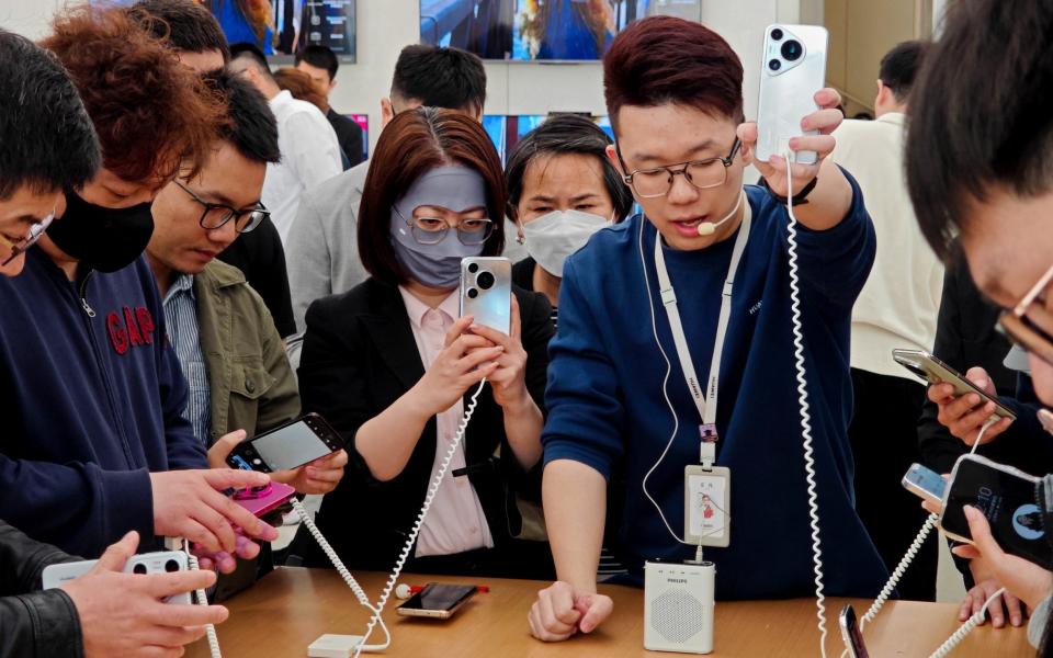 People try Huawei's latest Pura 70 series phone at a store in Shanghai