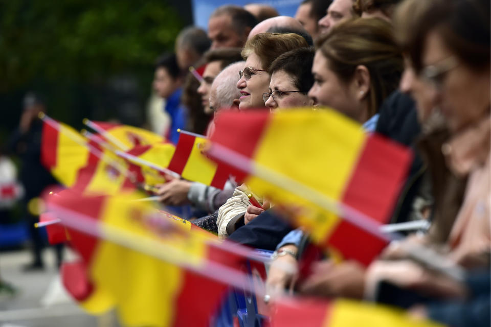 Gente ondea banderas españolas mientras esperan la llegada del rey Felipe VI y la reina Letizia a la ceremonia de los Premios Princesa de Asturias en Oviedo, en el norte de España, el viernes 19 de octubre del 2018. (AP Foto/Alvaro Barrientos)