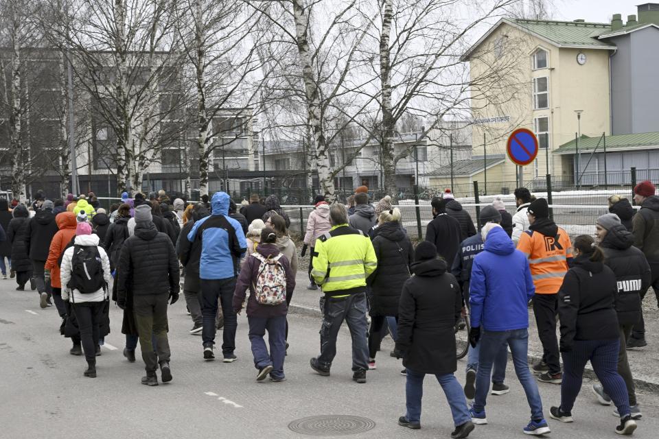 Police officers lead family members of pupils of the Viertola comprehensive school before entering the school, in Vantaa, Finland, Tuesday, April 2, 2024. A 12-year-old student opened fire at a secondary school in southern Finland on Tuesday morning, killing one and seriously wounded two other students, police said. The suspect was later arrested. (Markku Ulander/Lehtikuva via AP)