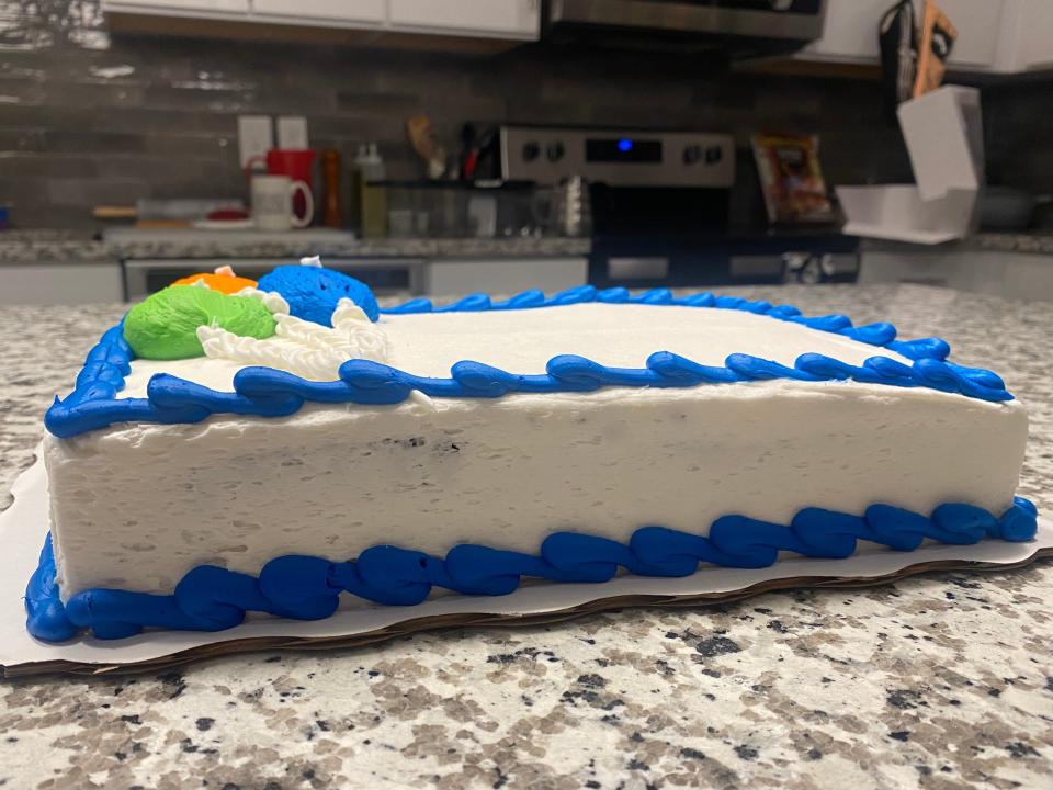 side view of a sheet cake, one layer covered in white frosting with a blue border above and below