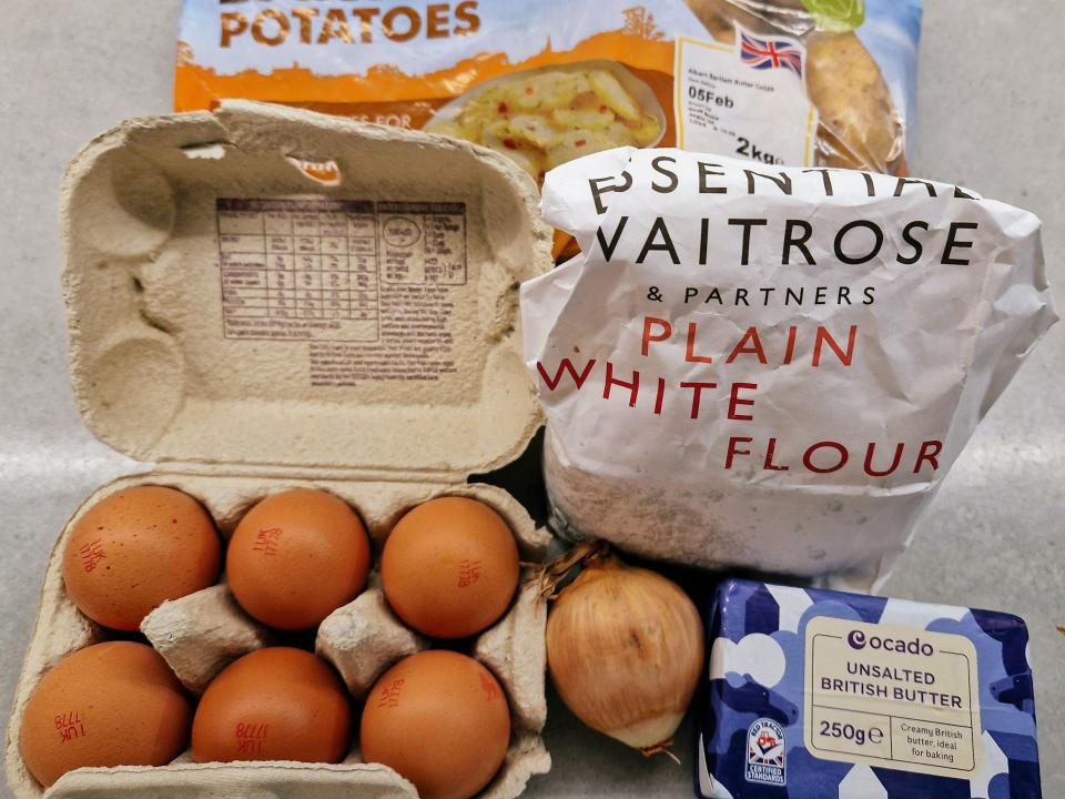 potatoes, eggs, flour, an onion, and butter on a counter