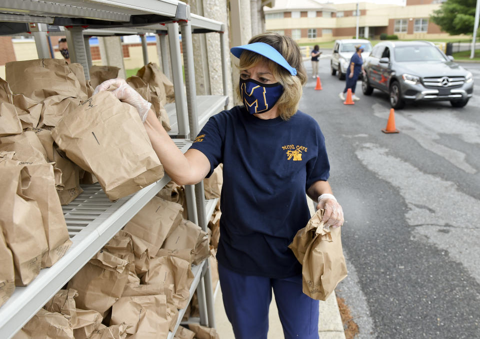 Joan Sandritter, a cafeteria worker, gets grab-and-go breakfasts and lunches from a rack, to distribute them to families who drive up at Muhlenberg Elementary Center in Muhlenberg Twp., PA. (Photo by Ben Hasty/MediaNews Group/Reading Eagle via Getty Images)