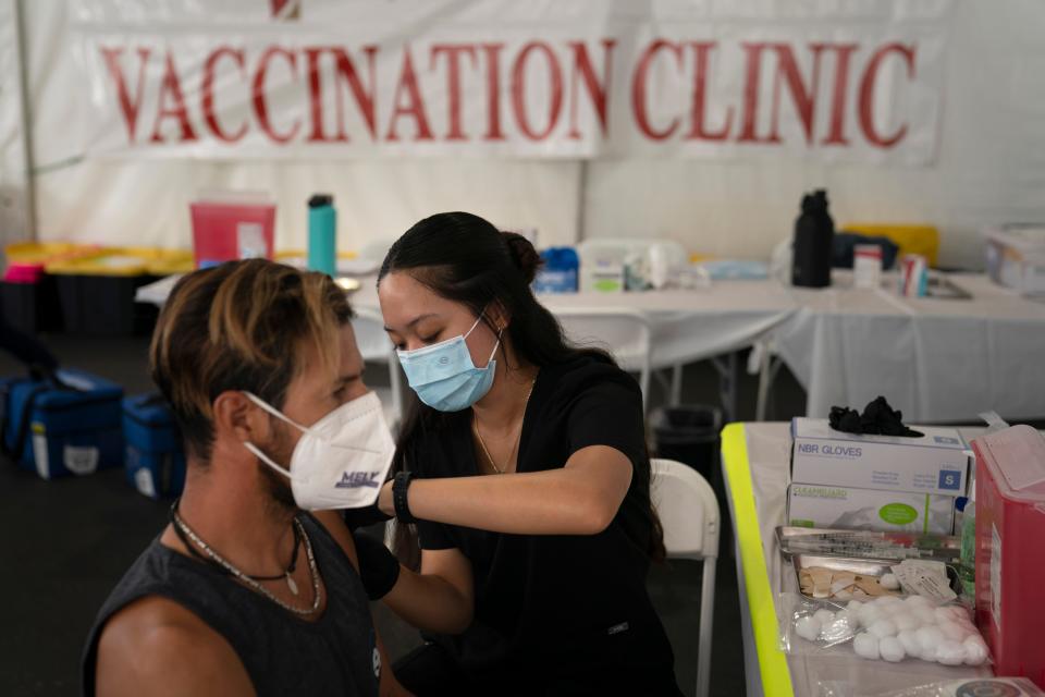 Registered nurse Noleen Nobleza, center, inoculates Julio Quinones with a COVID-19 vaccine on Aug. 28 at a clinic set up in the parking lot of CalOptima in Orange, California.