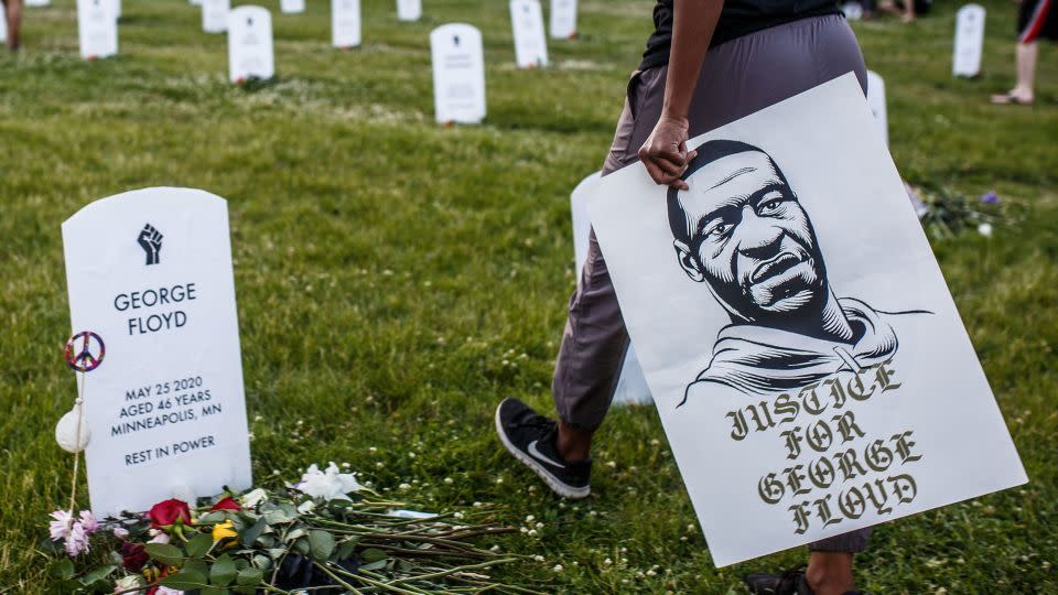 A person holds a sign displaying a portrait of George Floyd during a vigil at an art installation honoring victims of police burtaliuty in Minneapolis in June 2020. (Kerem Yucel/AFP/Getty Images) - Kerem Yucel/AFP/Getty Images