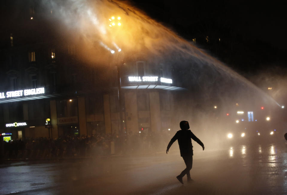 FILE - In this Dec.12, 2020 file photo, a man walks toward a police water canon during a protest against a proposed security bill in Paris. France's parliament is set to approve a security bill to extend police powers that has prompted criticism from civil rights activists who fear it would threaten efforts to denounce police abuse. (AP Photo/Thibault Camus)