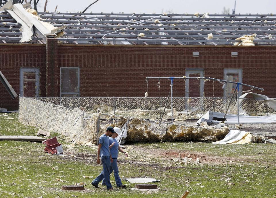 Workers walk past damage at South Lincoln Elementary School on Tuesday, April 29, 2014, after storms came through Monday in Fayetteville, Tenn. (AP Photo/Mark Humphrey)