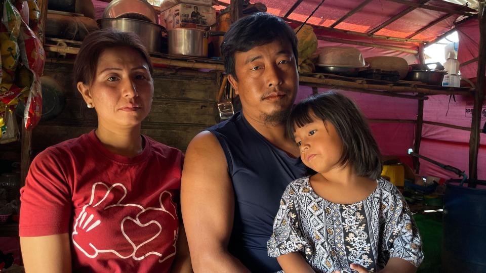 A couple are seen with their little girl in front of a makeshift kitchen