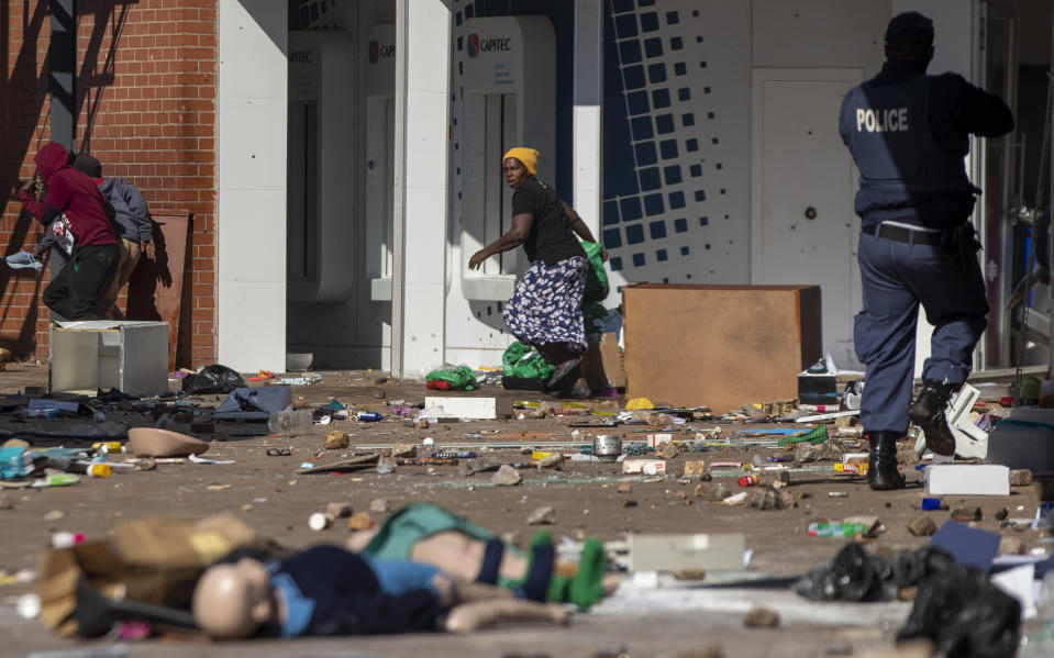 People run for cover whilst police officer fire rubber bullets as they attempt looting at Letsoho Shopping Centre in Katlehong, east of Johannesburg, South Africa, Monday, July 12, 2021. Police say six people are dead and more than 200 have been arrested amid escalating violence during rioting that broke out following the imprisonment of South Africa's former President Jacob Zuma. (AP Photo/Themba Hadebe)